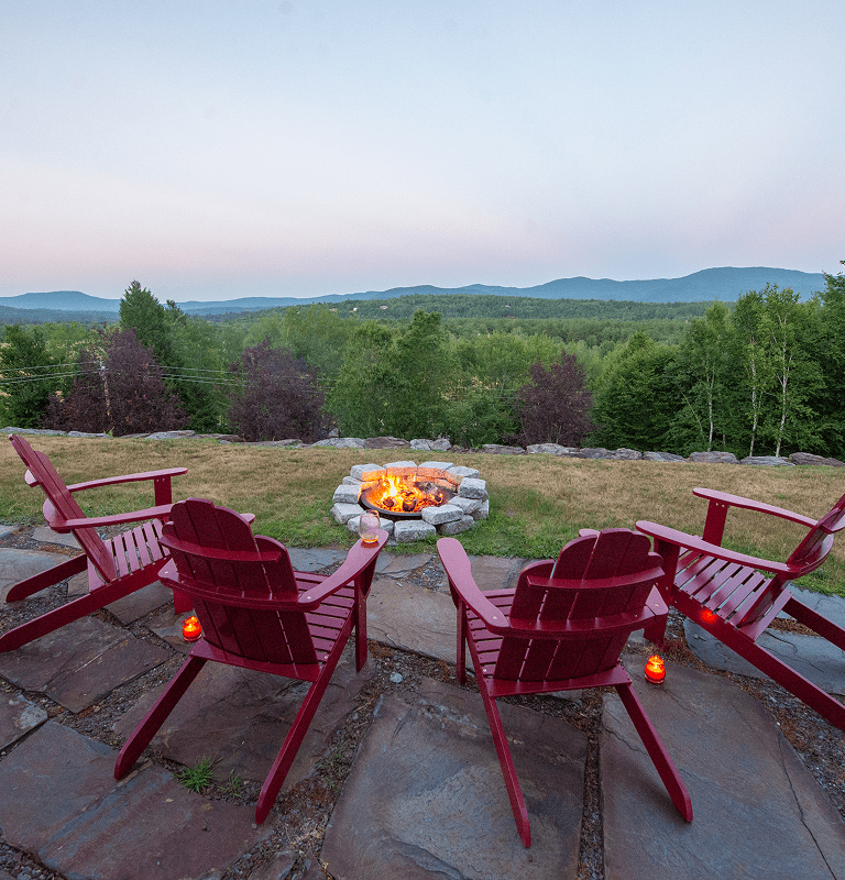 Red Adirondack chairs around stone fire pit