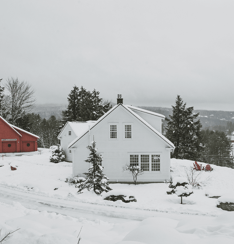 Snow-covered white house with red barn
